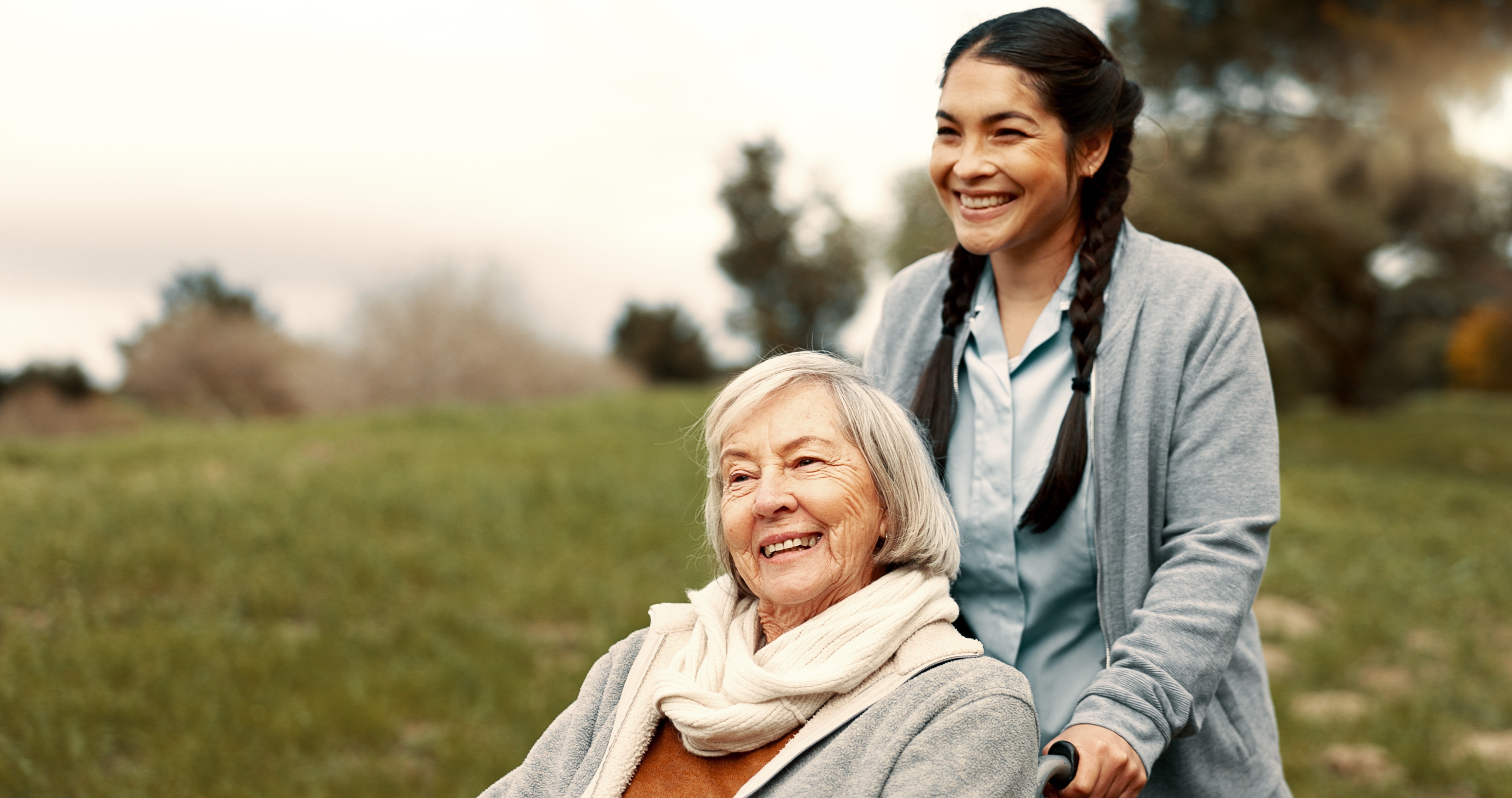 Caregiver with elderly client in wheelchair outdoors